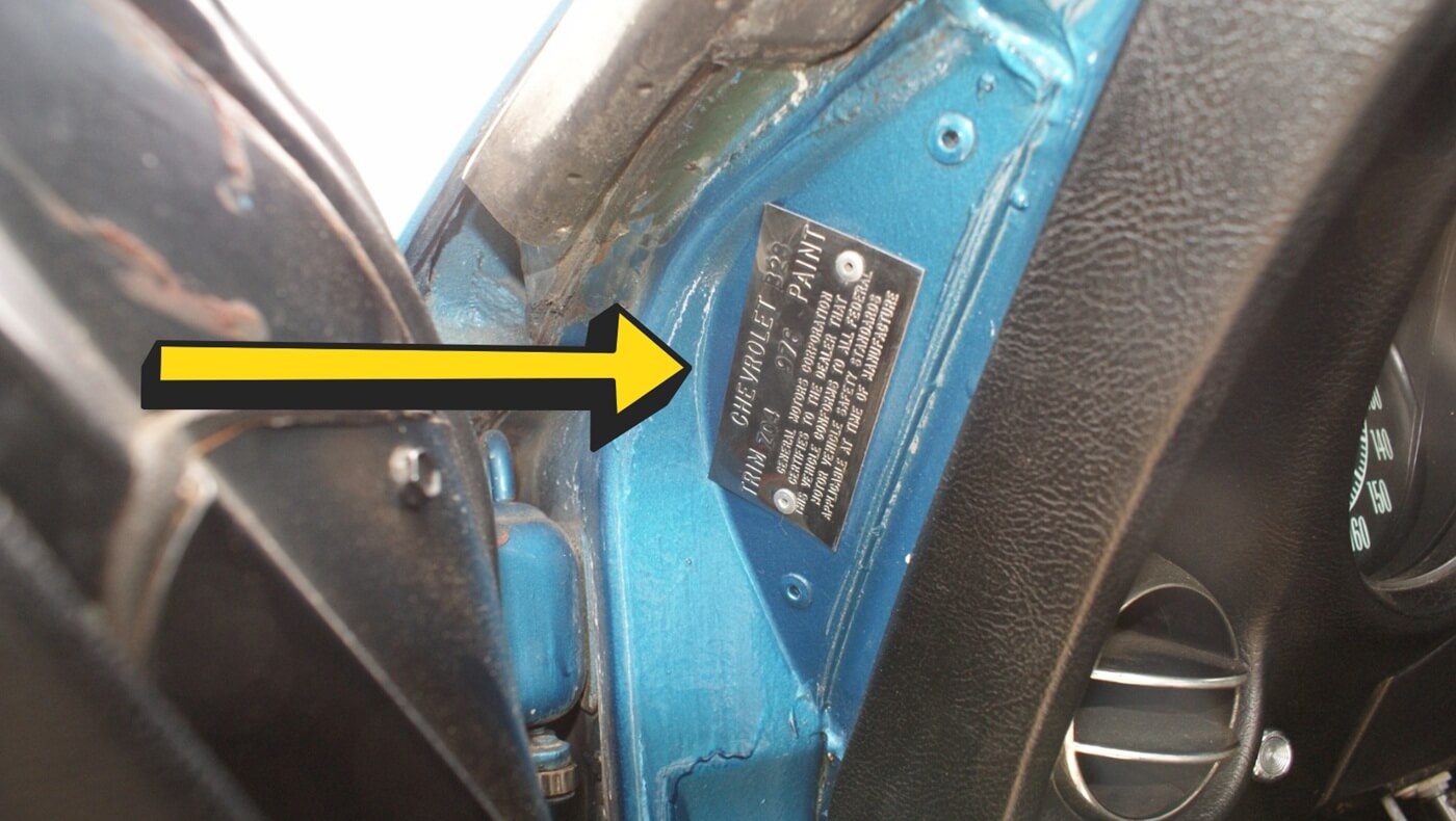 Trim tag or trim plate location above the driver's upper door hinge in Corvette C3 models (1968-1982), used for identifying options and features.